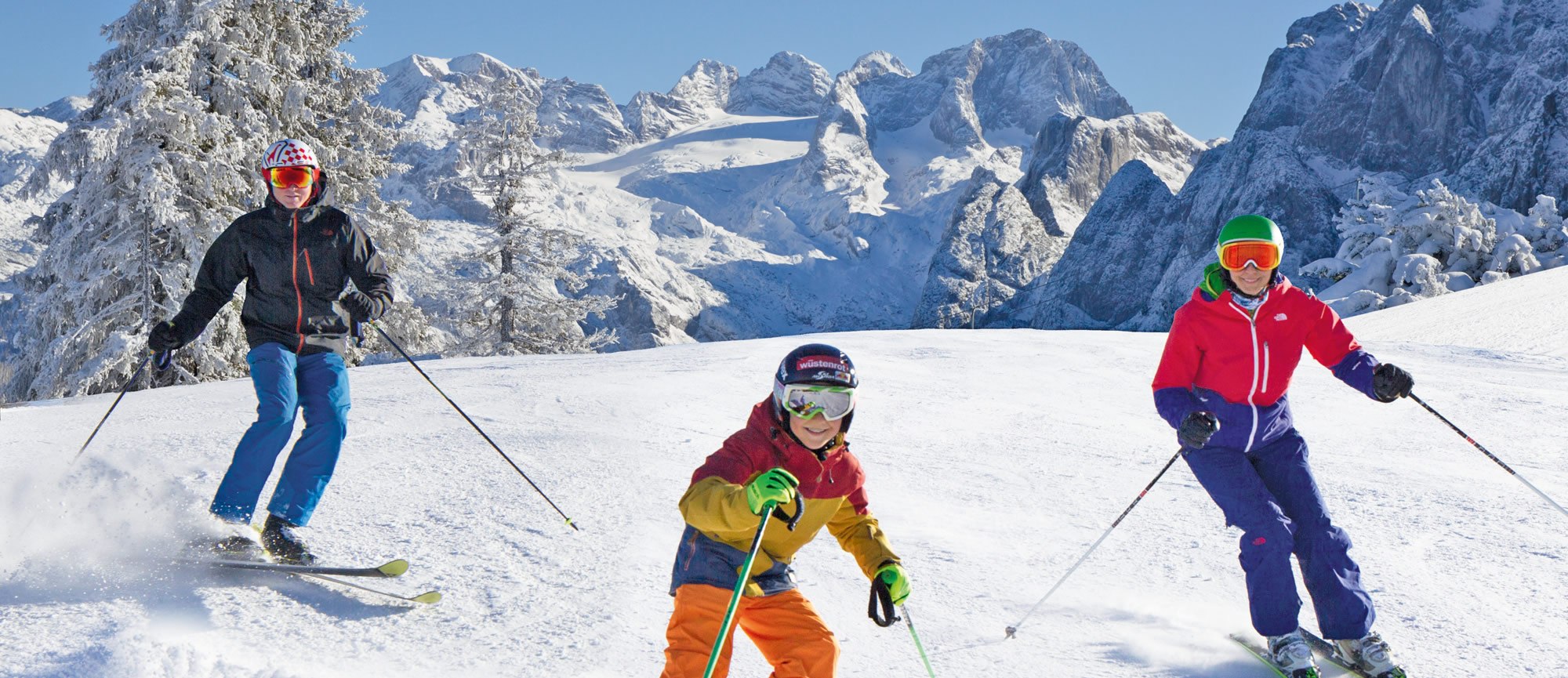 Familien beim Skifahren in der Skiregion Dachstein-West, im Hintergrund der Gosau Gletscher